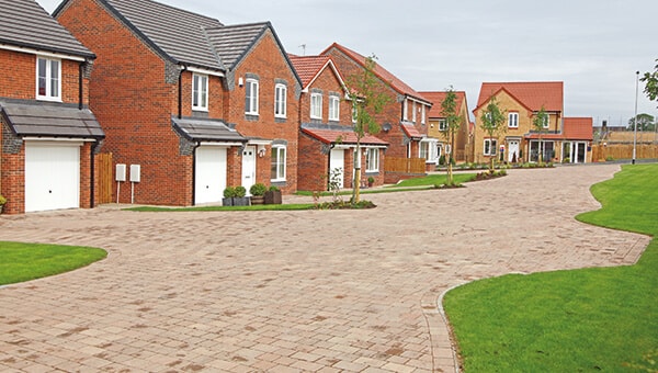 A row of new houses, with brick driveways.