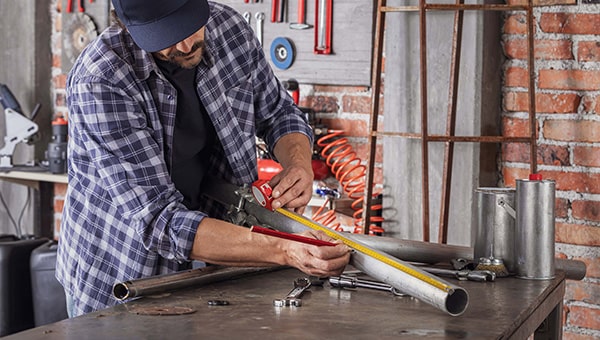 Man measuring pipe with a tape measure.