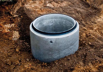 A concrete manhole ring being installed in the ground.
