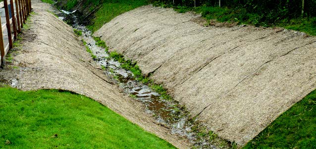 An erosion control blanket installed in an irrigation ditch.
