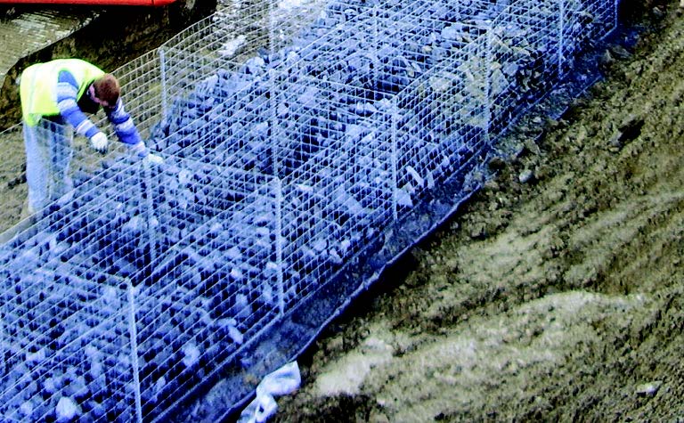 A gabion wall being installed with a contractor in the foreground.