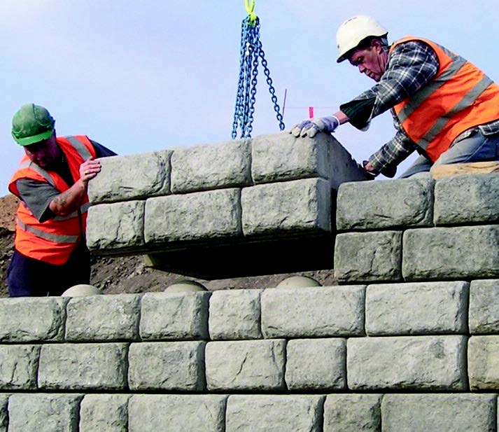 Redi-Rock being laid by two contractors.