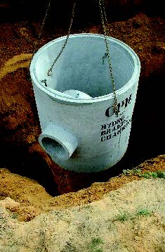 A concrete flow control chamber being lowered into the ground.