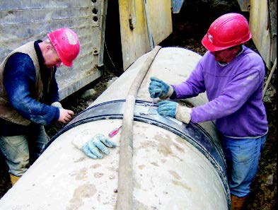 A large flexible coupler joining two sections of concrete pipe.